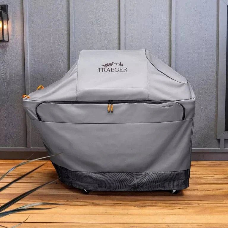 Traeger grill cover on a wooden deck with a gray wall background