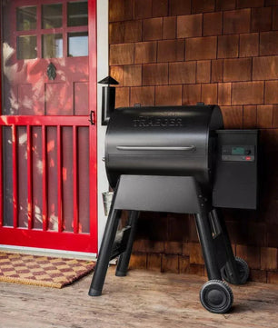 Black grill on a wooden deck with a red door in the background