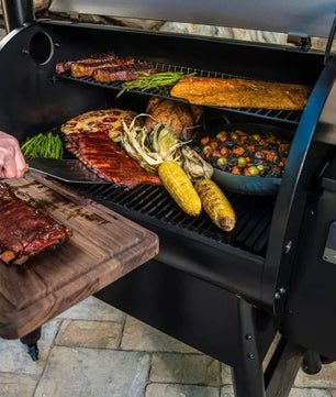 Person grilling meat and vegetables on a barbecue with various condiments nearby.
