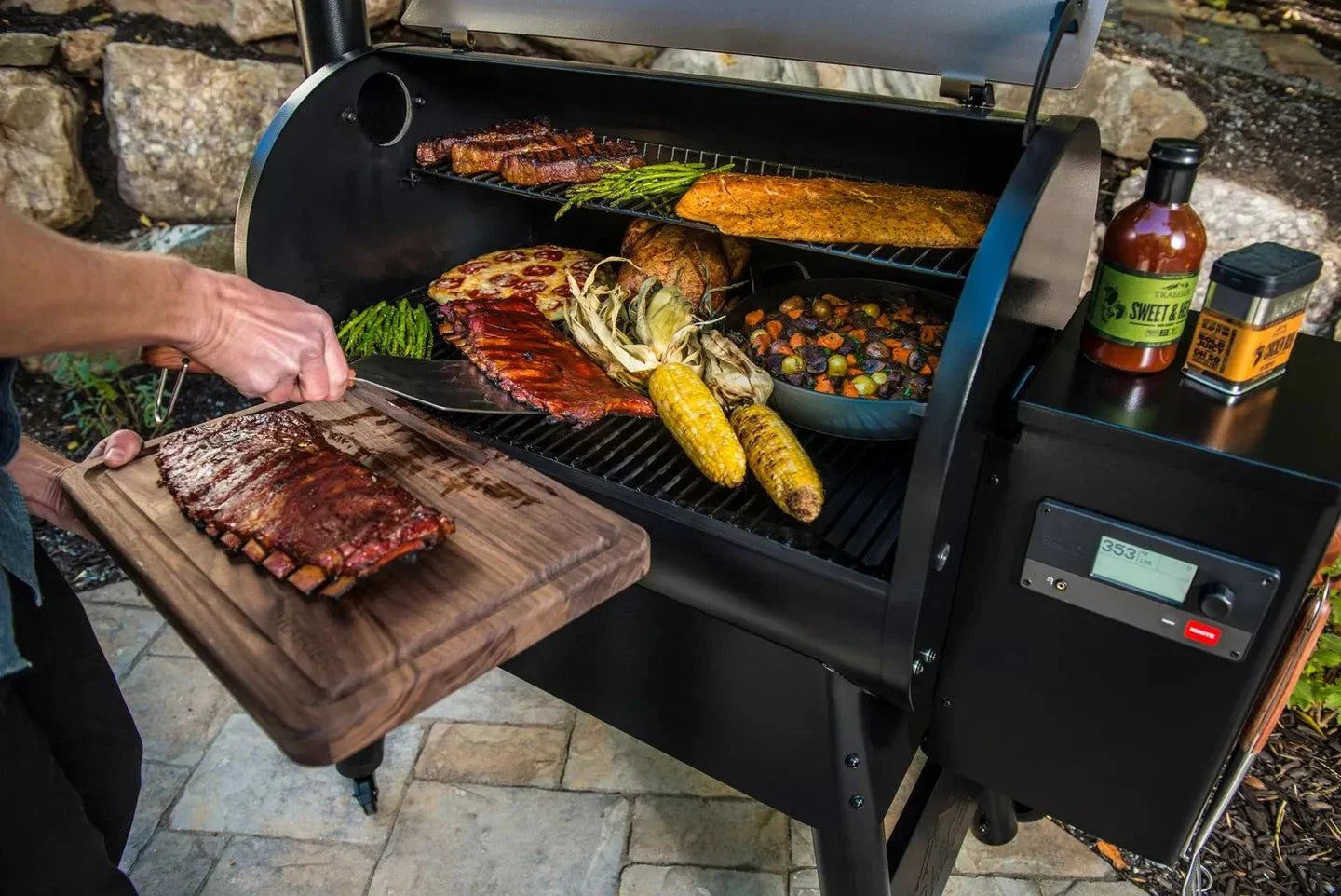 Person grilling meat and vegetables on a barbecue with various condiments nearby.