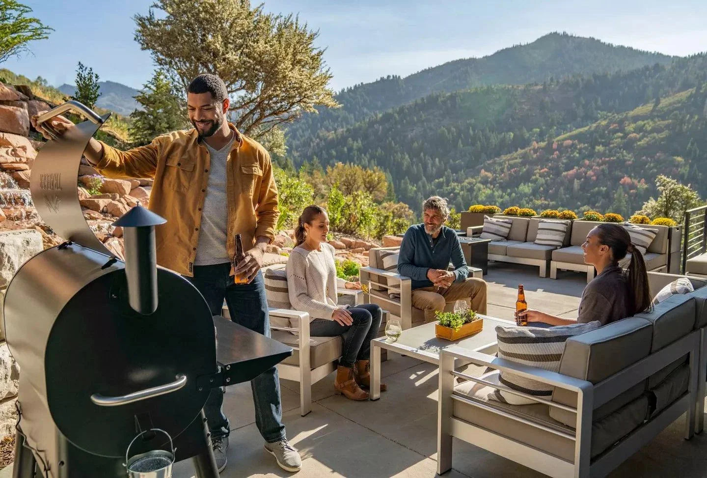 Group of people enjoying a barbecue outdoors with mountains in the background