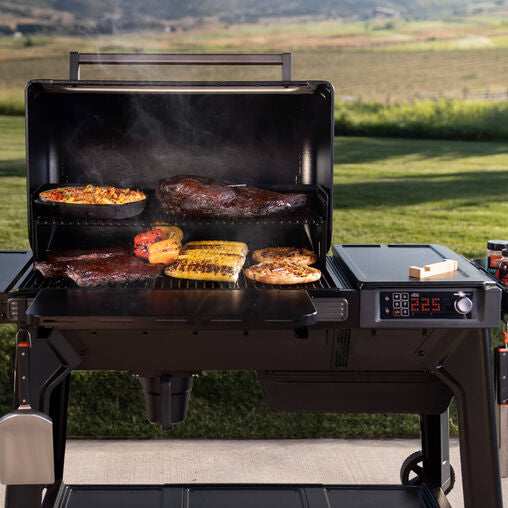 Portable grill with food cooking outdoors on a grassy area