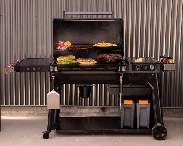 Multifunctional grill with cooking area and side burners on a gray background