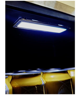 A rectangular LED light bar emitting a bright blue light, mounted on a dark ceiling above yellow chairs.