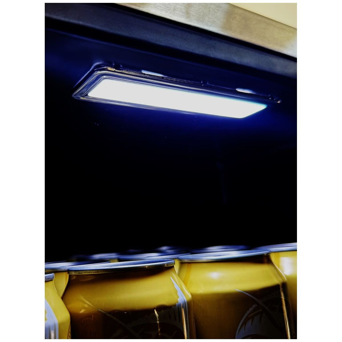 A rectangular LED light bar emitting a bright blue light, mounted on a dark ceiling above yellow chairs.