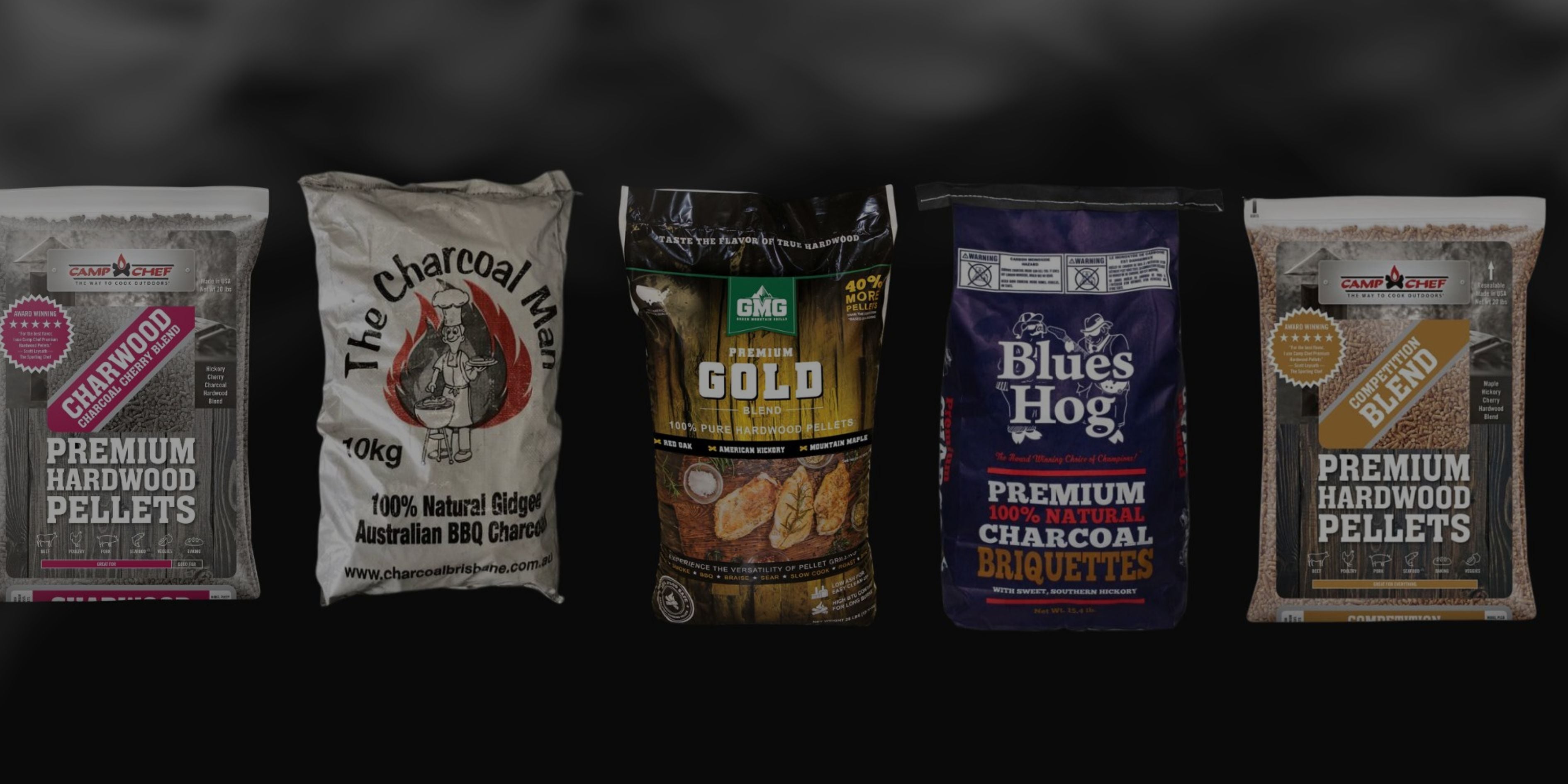 Five bags of different brands of charcoal and wood pellets on a black background