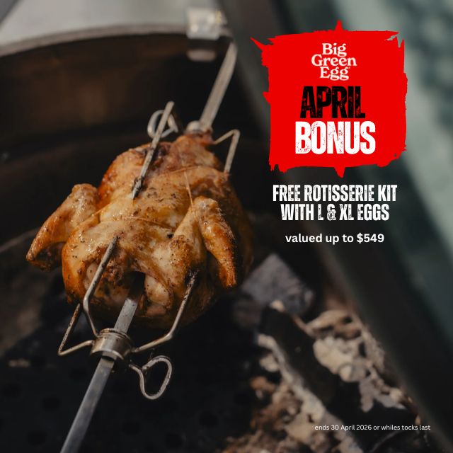 Roasted chicken on a rotisserie over a grill with Big Green Egg April Bonus offer text.