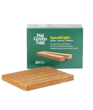 A package of Big Green Egg SpeedLight natural charcoal starter sticks, with one rectangular wood stick displayed in front of the green box on a white background.