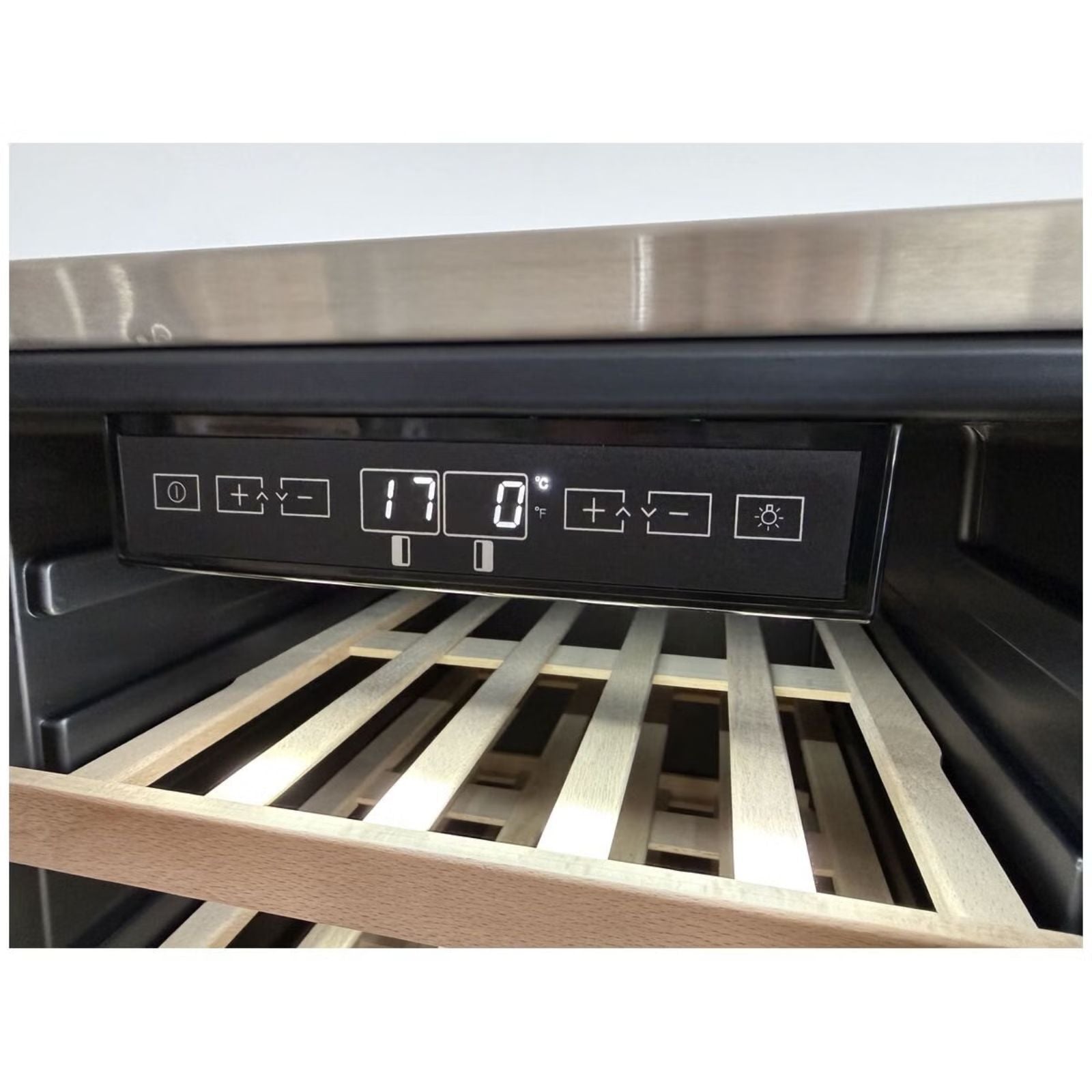 Close-up of a wine cooler control panel with a digital display and buttons, set inside a stainless steel wine refrigerator with wooden slatted shelves visible.