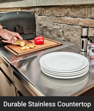 Person preparing food on a stainless steel countertop with stacked white plates and a pepper.