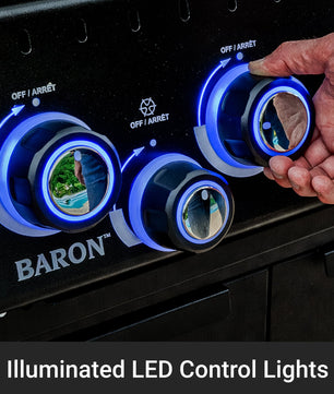 Close-up of a black gas grill control panel with three illuminated blue LED control lights and a hand turning one of the knobs. The BARON brand name is visible on the panel, and a text overlay at the bottom reads 'Illuminated LED Control Lights'.