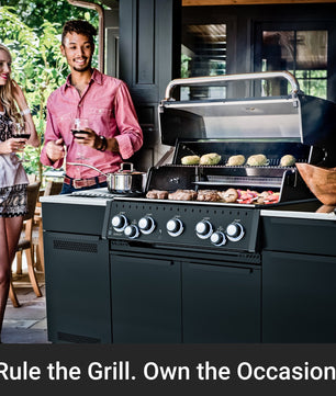 A large black outdoor gas grill with six control knobs is shown open, cooking meat and burgers on a patio. Two people holding wine glasses stand to the left, and a dark promotional banner at the bottom reads, 'Rule the Grill.