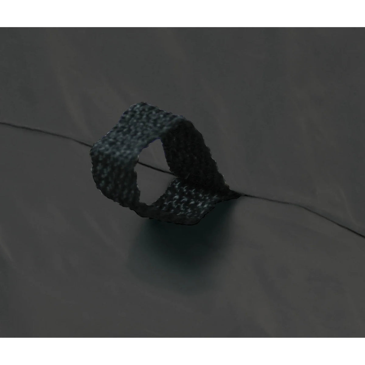 Close-up of a dark gray or black textured strap or loop attached to a dark fabric surface.