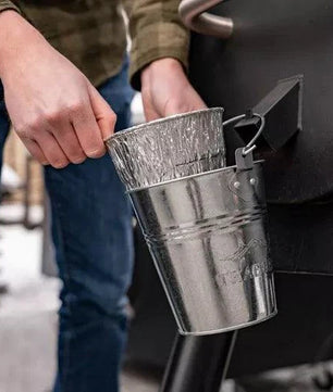 Person holding a metal funnel over a barbecue grill