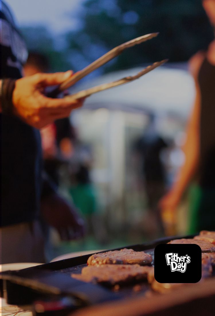 Person grilling food with skewers on a grill, blurred background with 'Father's Day' logo.
