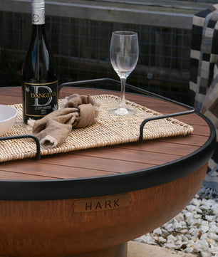 Outdoor fire pit table with wine bottle and glasses on a patio