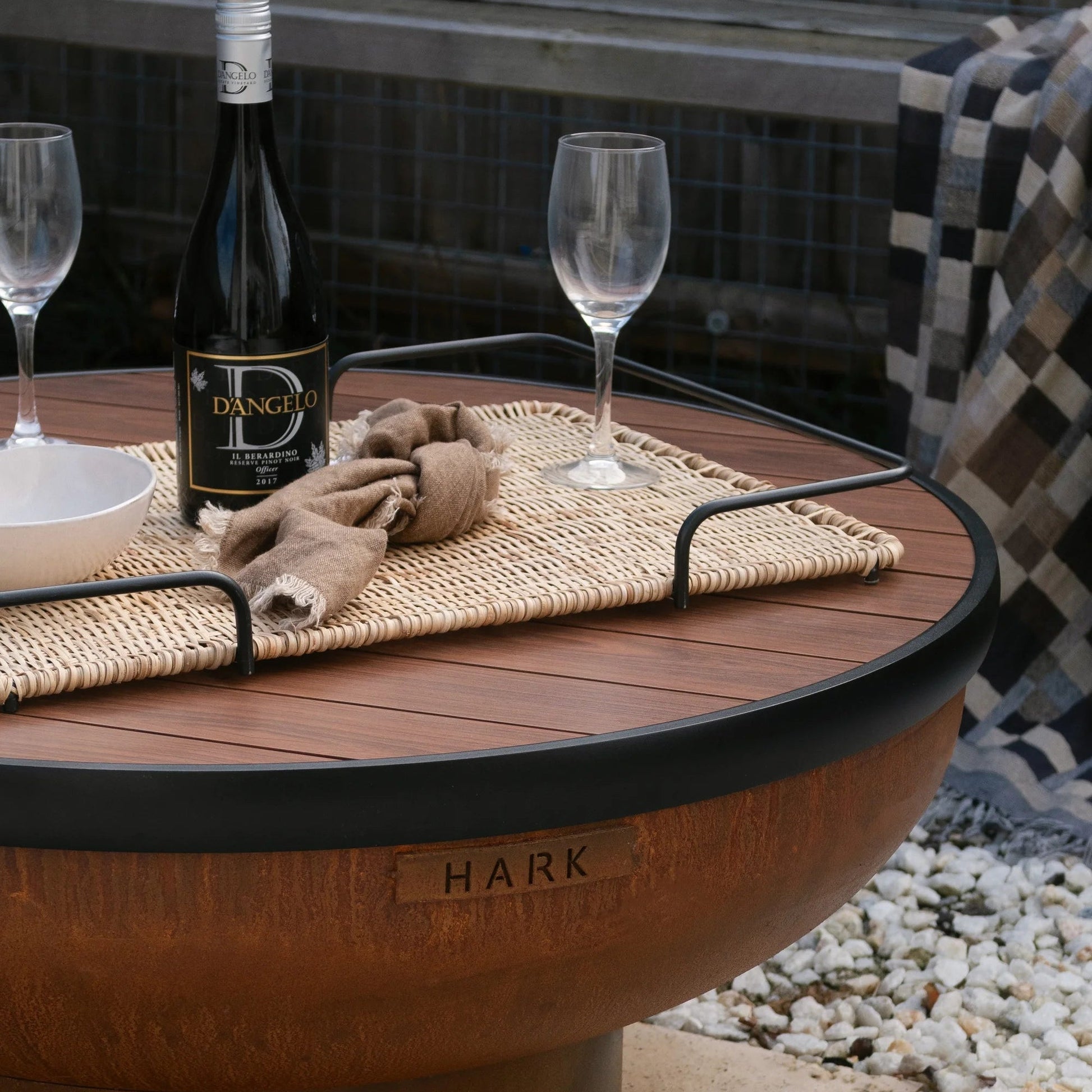 Outdoor fire pit table with wine bottle and glasses on a patio