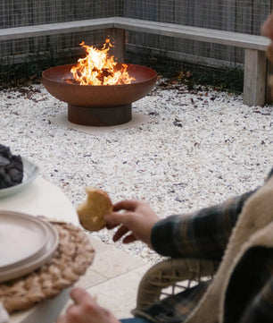Person sitting by a fire pit in an outdoor setting