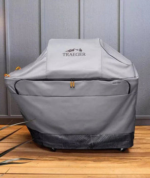 Traeger grill cover on a wooden deck with a gray wall background