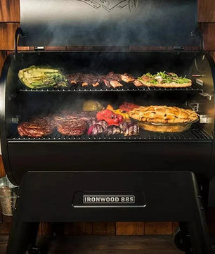 Black smoker grill with food cooking inside against a wooden wall.