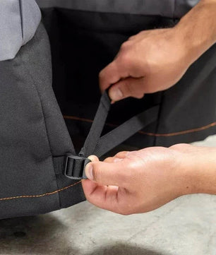 Person adjusting a black strap on a gray bag.