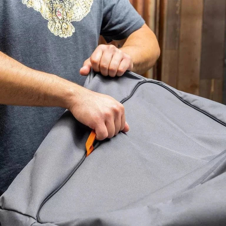 Person using a tool to open a gray garment bag.