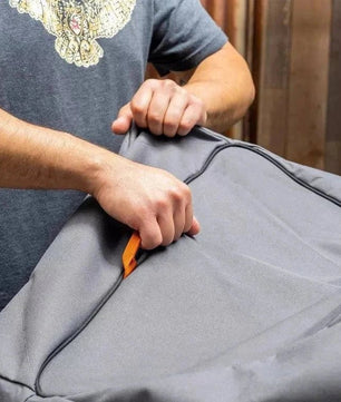 Person using a tool to open a gray garment bag.