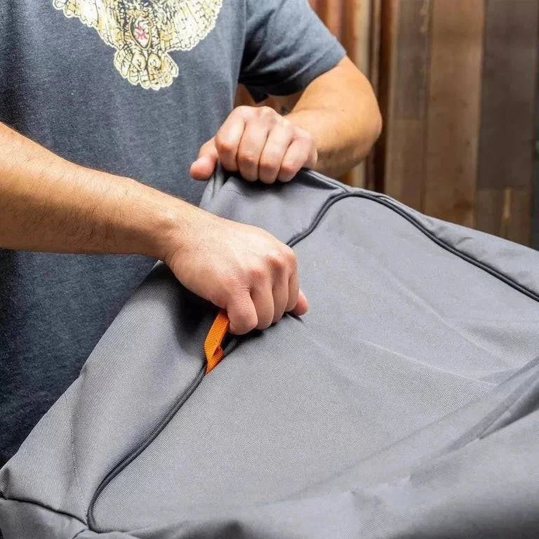 Person using a tool to open a gray garment bag.