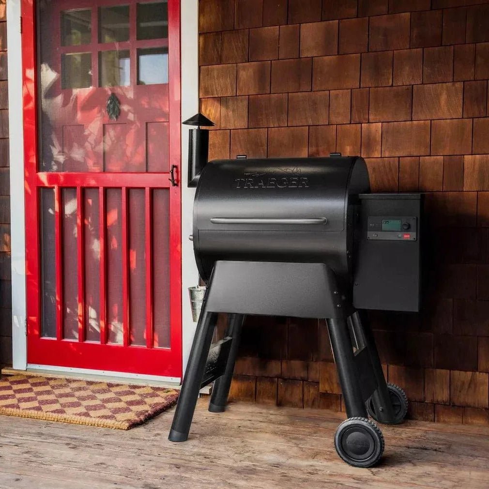 Black grill on a wooden deck with a red door in the background