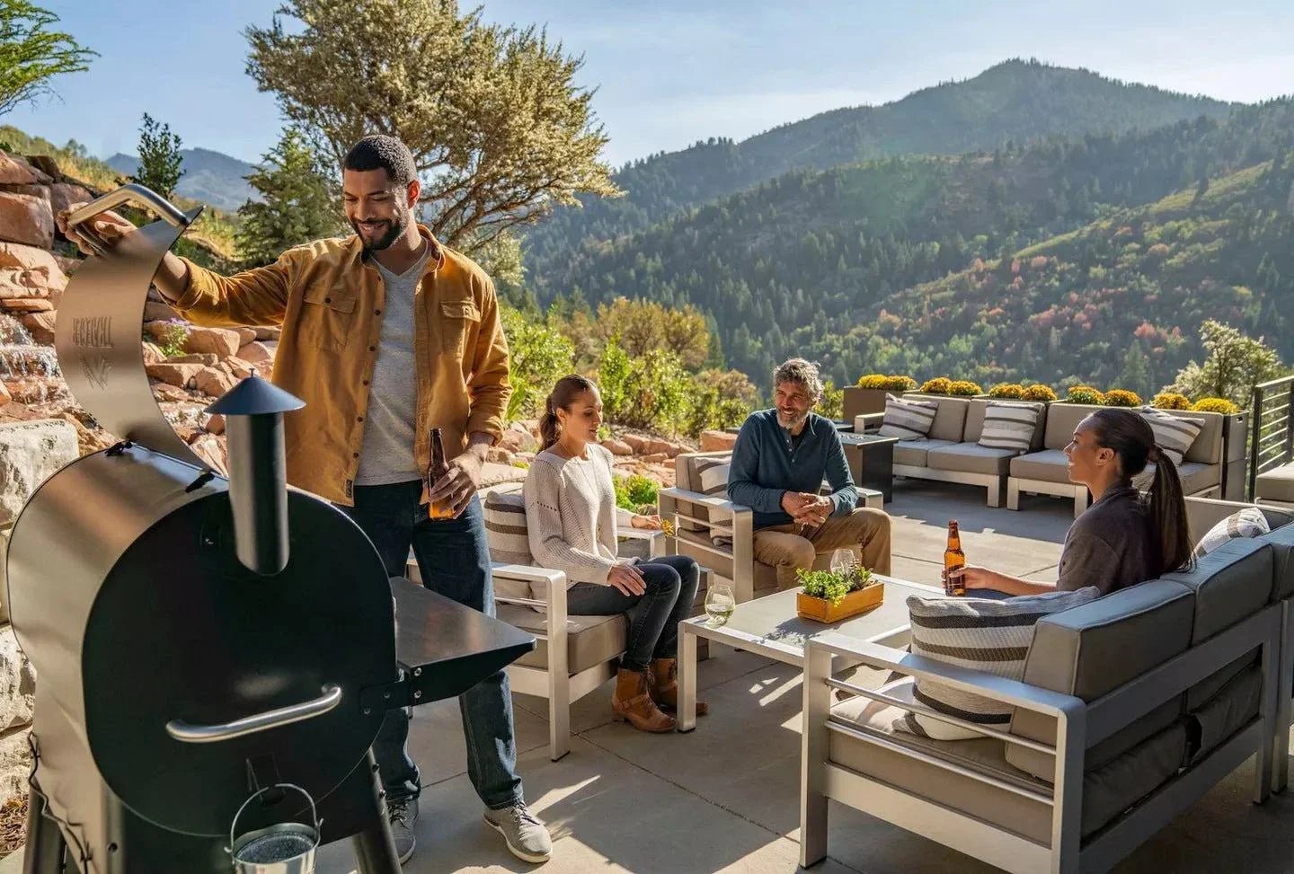 Group of people enjoying a barbecue outdoors with mountains in the background