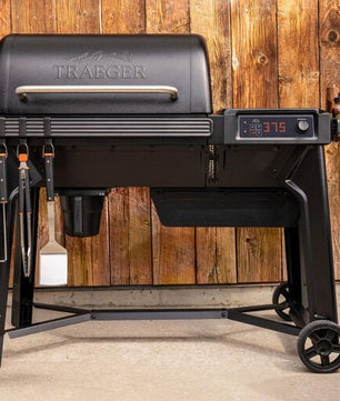 Black Traeger grill with digital display against a wooden wall background