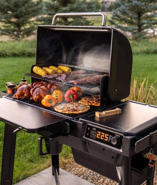 Portable grill with food on a grassy outdoor setting