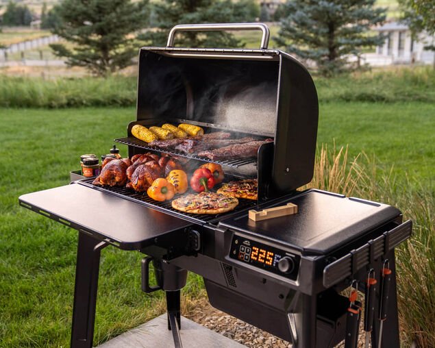 Portable grill with food on a grassy outdoor setting