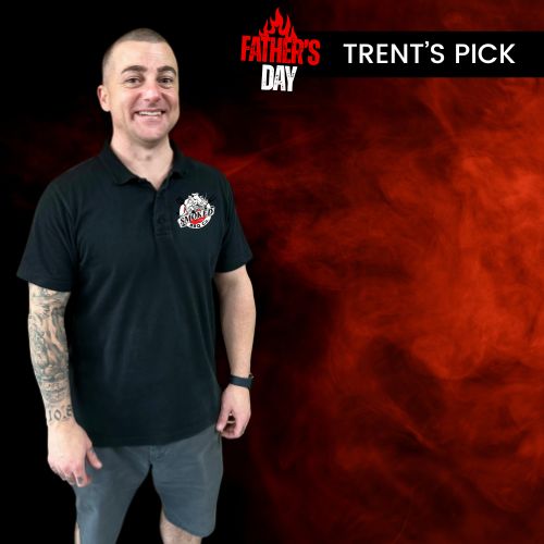 A man wearing a black short-sleeve polo shirt with a small white and red crest logo on the left chest, standing against a dark background with a red smoky graphic and text reading 'FATHER'S DAY' and 'TRENT'S PICK'.